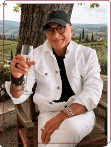 Marco, co-founder of Baroque Bacchus, relaxing with a glass of sparkling wine against a panoramic view of the Tuscan countryside