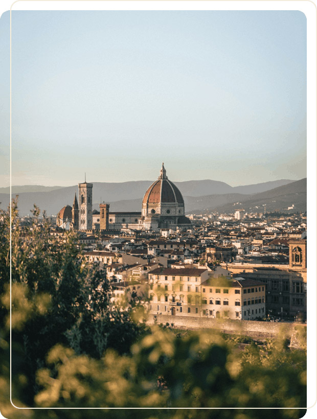 Vertical panoramic view of Florence cityscape framed by green foliage, showing Brunelleschi's Dome and Giotto's Bell Tower during a Baroque Bacchus tour