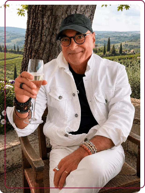 Marco, co-founder of Baroque Bacchus, relaxing with a glass of sparkling wine against a panoramic view of the Tuscan countryside